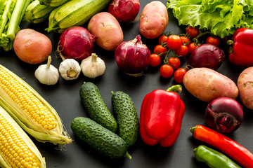 Fresh vegetables still life. Potato, cucumber, beet carrot, greenery on black background