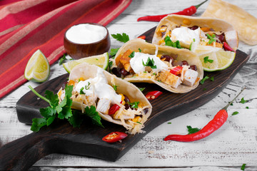 Tacos on corn tortilla with chicken and vegetables topped with sour cream. Mexican cuisine meal