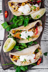 Tacos on corn tortilla with chicken and vegetables topped with sour cream. Mexican cuisine meal