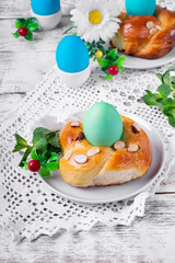 Easter yeast bun ring with almond and colored egg in the middle on the white wooden table