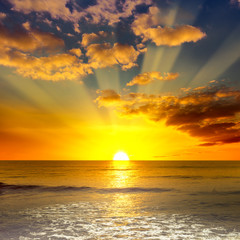 Majestic bright sunrise over ocean and orange clouds