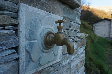 Ancient stone fountain with brass tap