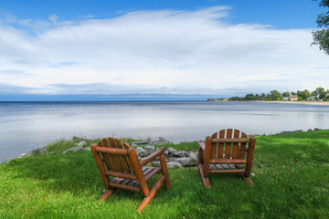 Peaceful view of two wooden chairs facing the lac St Jean, in Quebec
