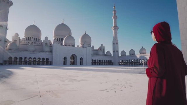 Woman Wearing Traditional Abaya Dress Standing and Looking at Sheikh Zayed Grand Mosque as She Visits Abu Dhabi in United Arab Emirates (UAE)