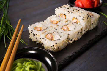 Set of sushi rolls with wasabi and ginger on a black background. Japanese oriental cuisine