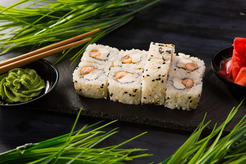 Set of sushi rolls with wasabi and ginger on a black background. Japanese oriental cuisine