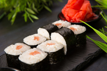 Set of sushi rolls with wasabi and ginger on a black background. Japanese oriental cuisine