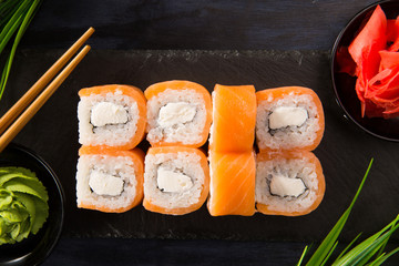 Set of sushi rolls with wasabi and ginger on a black background. Japanese oriental cuisine