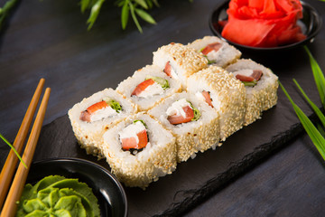 Set of sushi rolls with wasabi and ginger on a black background. Japanese oriental cuisine