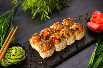 Set of baked sushi rolls with wasabi and ginger on a black background. Japanese oriental cuisine