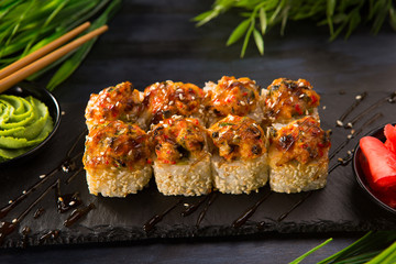 Set of baked sushi rolls with wasabi and ginger on a black background. Japanese oriental cuisine