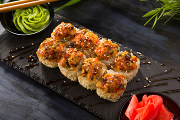 Set of baked sushi rolls with wasabi and ginger on a black background. Japanese oriental cuisine