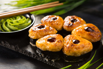 Set of baked sushi rolls with wasabi and ginger on a black background. Japanese oriental cuisine