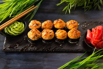 Set of baked sushi rolls with wasabi and ginger on a black background. Japanese oriental cuisine