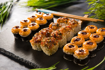 Set of baked sushi rolls with wasabi and ginger on a black background. Japanese oriental cuisine