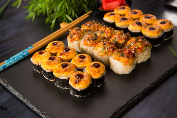 Set of baked sushi rolls with wasabi and ginger on a black background. Japanese oriental cuisine