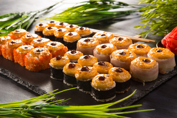 Set of baked sushi rolls with wasabi and ginger on a black background. Japanese oriental cuisine