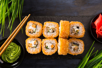 Set of baked sushi rolls with wasabi and ginger on a black background. Japanese oriental cuisine