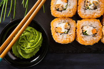 Set of baked sushi rolls with wasabi and ginger on a black background. Japanese oriental cuisine