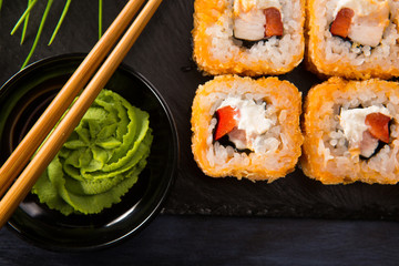 Set of baked sushi rolls with wasabi and ginger on a black background. Japanese oriental cuisine