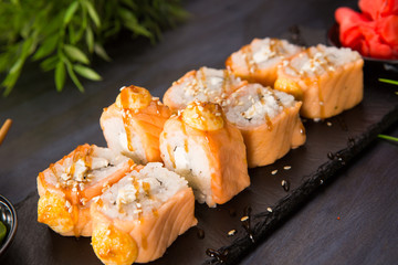 Set of baked sushi rolls with wasabi and ginger on a black background. Japanese oriental cuisine
