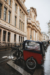 A vintage bicycle stands near a stone historic building. Retro transport for transporting people. Bicycle taxis in Paris, France.