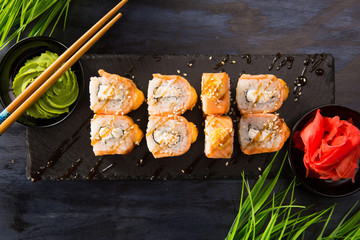 Set of baked sushi rolls with wasabi and ginger on a black background. Japanese oriental cuisine