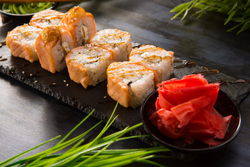Set of baked sushi rolls with wasabi and ginger on a black background. Japanese oriental cuisine