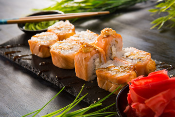 Set of baked sushi rolls with wasabi and ginger on a black background. Japanese oriental cuisine