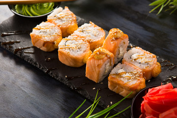 Set of baked sushi rolls with wasabi and ginger on a black background. Japanese oriental cuisine