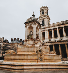 Obraz premium The Roman Catholic Church of Saint-Sulpice in Paris, France. Square with a fountain in front of the facade. Sculptures of saints and lions adorn the fountain.