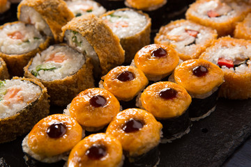 Set of baked sushi rolls with wasabi and ginger on a black background. Japanese oriental cuisine