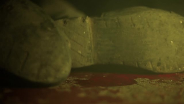 Cinematic shot of man's shoes with full of blood lying on the floor and suffering through it. B roll or B reel.