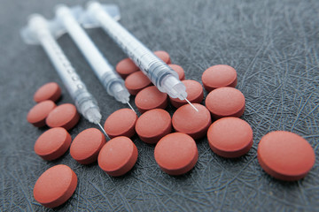 Close up of red pills and syringe on table 