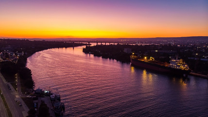 Aerial view of a docked ship near a bridge during sunset