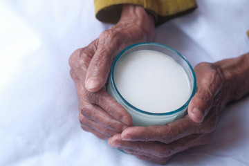 close up of senior women hand drinking milk