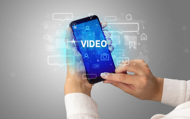 Female hand typing on smartphone with VIDEO inscription, social media concept