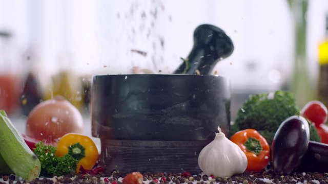 Spices and garlic fly into stone mortar, front view