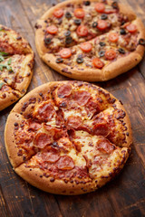 Composition of three various kinds pizzas on wooden table
