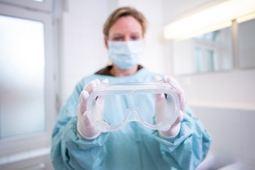 Female doctor in full protected medical suit holds a mouthpiece