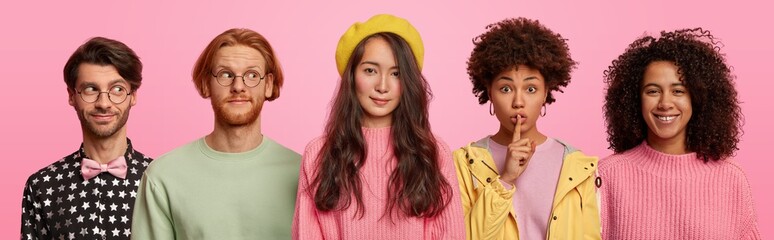 Horizontal shot of mixed young race women and men stand together against pink background, make silence gesture, smile and look gladfully thoughtfully aside, being in good mood. Collage image