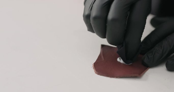 Slow motion man hands in black gloves test protective product on leather piece