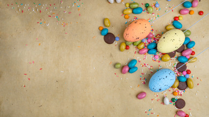 Colorful Easter eggs, sweets on yellow background, copy space