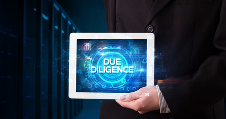 Young business person working on tablet and shows the inscription: DUE DILIGENCE, business concept