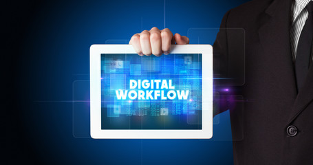 Young business person working on tablet and shows the inscription: DIGITAL WORKFLOW