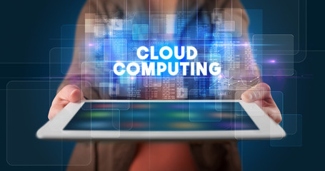Young business person working on tablet and shows the inscription: CLOUD COMPUTING