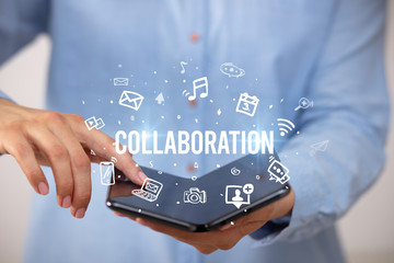 Businessman holding a foldable smartphone with COLLABORATION inscription, social media concept