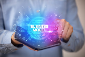 Businessman holding a foldable smartphone with BUSINESS MODEL inscription, new business concept