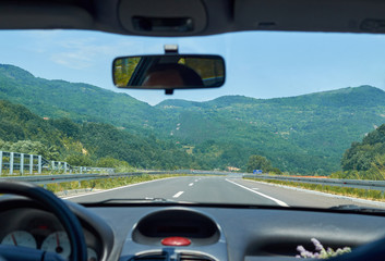 Asphalt highway through a picturesque landscape seen from a car in motion