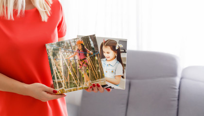A happy young blonde woman is holding a large wall canvas at home